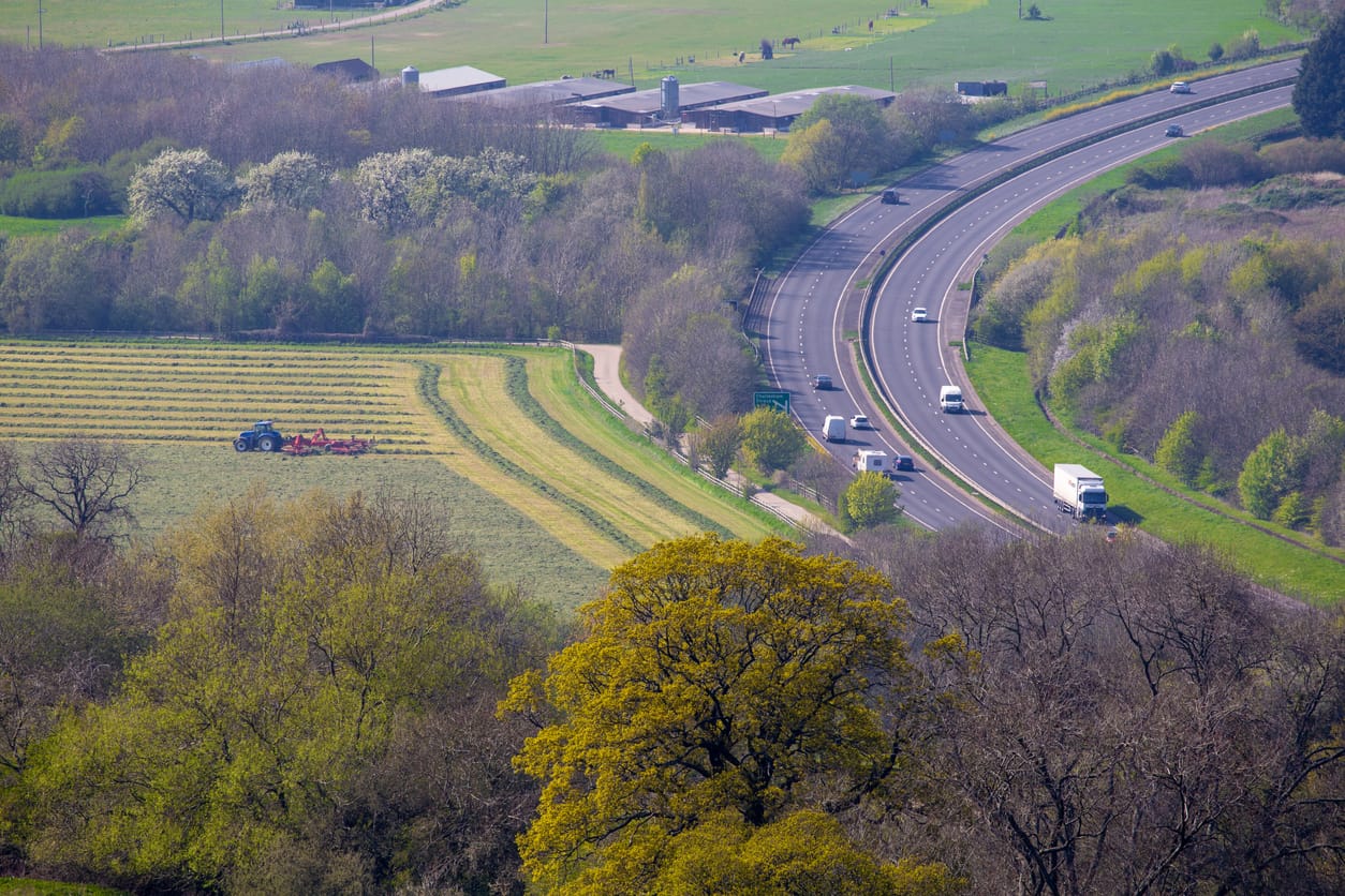 Elevated view of a dual carriageway slicing through the Cotswold landscape - highlighting the environmental problems with traffic pollution and  road infrastructure